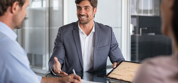 Man in a suit shaking hands with another person in an office setting